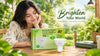 A woman sitting at a table, looking pleased while interacting with a "Brighten Your World" box.