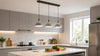 Modern kitchen with a marble island, fresh vegetables, pendant lights, and gray cabinets. Natural light streams through a large window, creating a cozy ambiance.