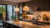 Modern kitchen with sleek cabinetry and a large island. Warm lighting from pendant lamps, with plants and organized cookware creating a cozy ambiance.